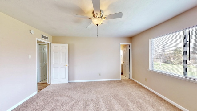 unfurnished bedroom featuring light carpet, ensuite bath, visible vents, and baseboards