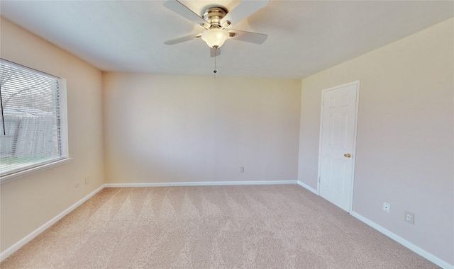 spare room with a ceiling fan, light colored carpet, and baseboards