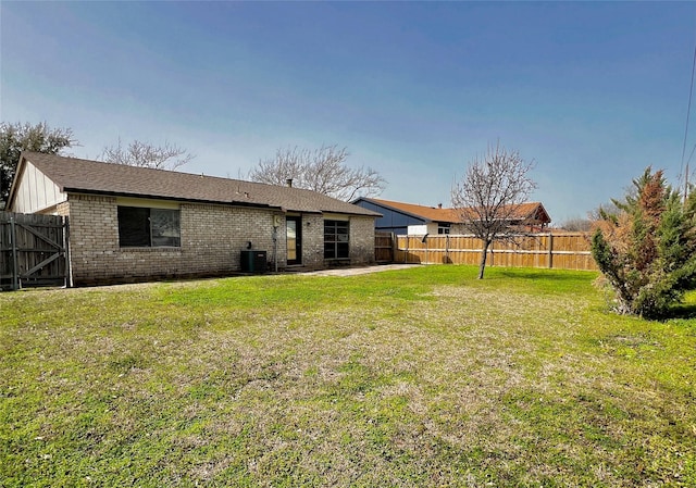 rear view of property featuring a yard, a patio, and a fenced backyard