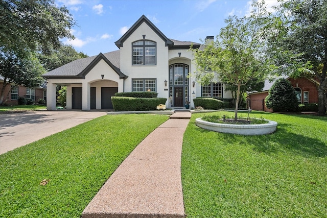 french country style house with concrete driveway, a chimney, an attached garage, a front yard, and stucco siding