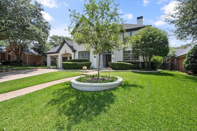 view of front facade with driveway, a front lawn, and a chimney