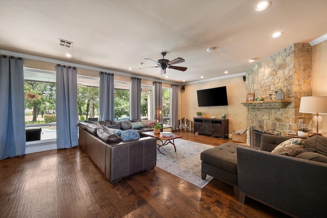 living room with a stone fireplace, visible vents, wood finished floors, and ornamental molding