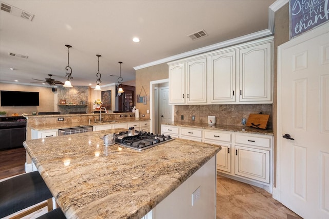 kitchen featuring visible vents, a kitchen island, open floor plan, a peninsula, and stainless steel gas cooktop