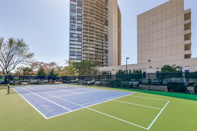 view of tennis court with community basketball court and fence