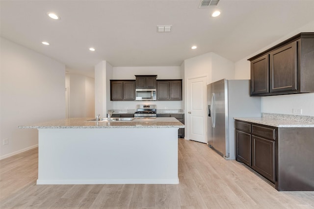 kitchen featuring a sink, dark brown cabinetry, appliances with stainless steel finishes, and an island with sink