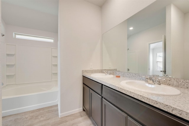 bathroom with double vanity, wood finished floors, baseboards, and a sink