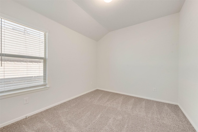 unfurnished room featuring vaulted ceiling, carpet, and baseboards