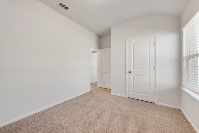 unfurnished bedroom with lofted ceiling, baseboards, visible vents, and light carpet