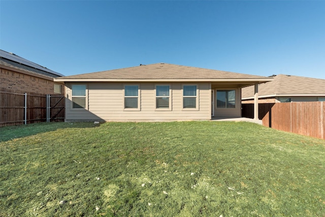 rear view of property with a yard and a fenced backyard