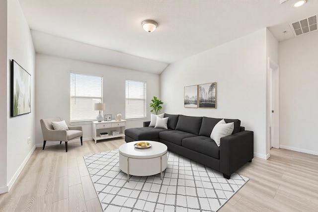 living area with visible vents, lofted ceiling, light wood-style floors, and baseboards