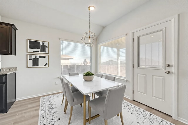 dining space with vaulted ceiling, light wood-style flooring, and baseboards