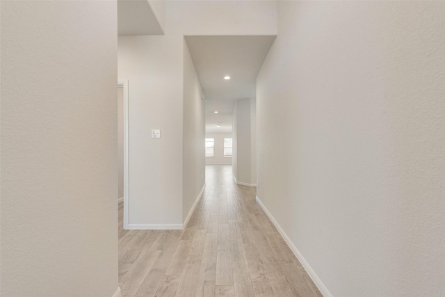 corridor featuring light wood finished floors, recessed lighting, and baseboards