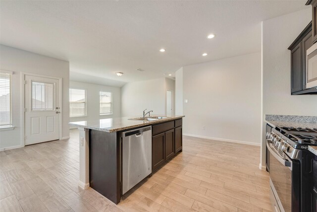 kitchen with a center island with sink, recessed lighting, light wood-style floors, stainless steel appliances, and a sink