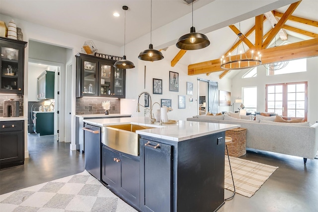 kitchen featuring tasteful backsplash, concrete floors, light countertops, stainless steel dishwasher, and a sink