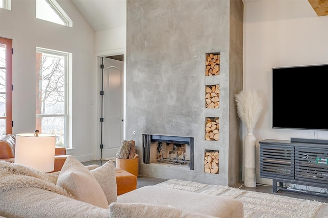 living area featuring a fireplace, a wealth of natural light, and high vaulted ceiling