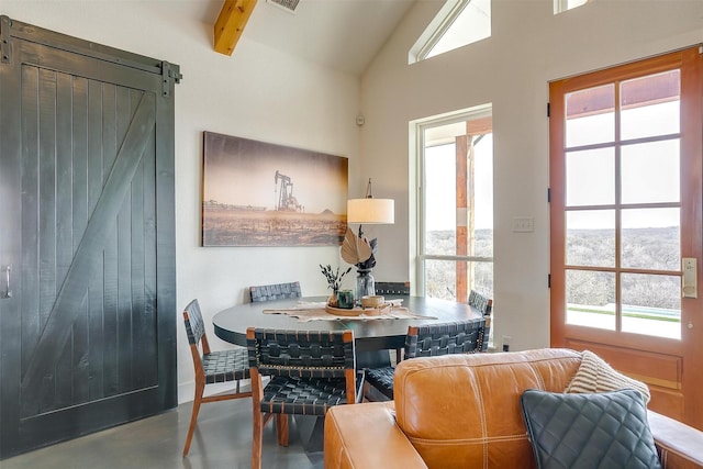 dining area with a barn door, lofted ceiling with beams, finished concrete flooring, and visible vents