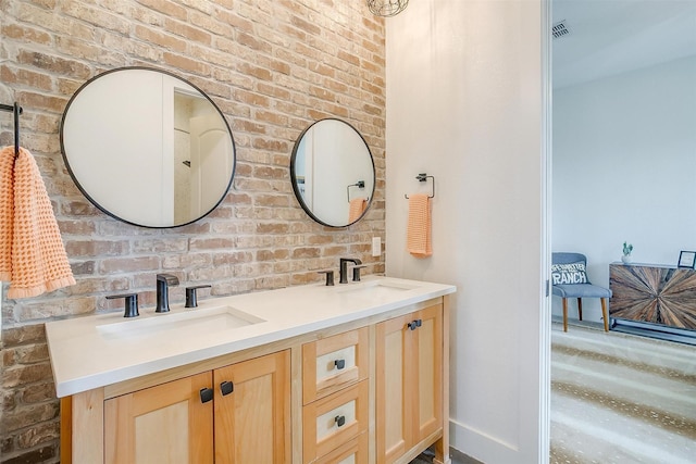 bathroom featuring double vanity, visible vents, brick wall, and a sink