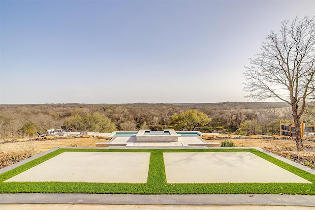 surrounding community featuring a swimming pool, a view of trees, and a patio