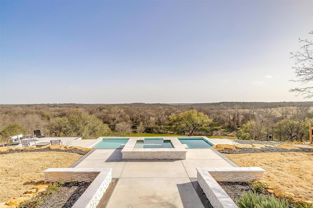 pool featuring a patio and a forest view