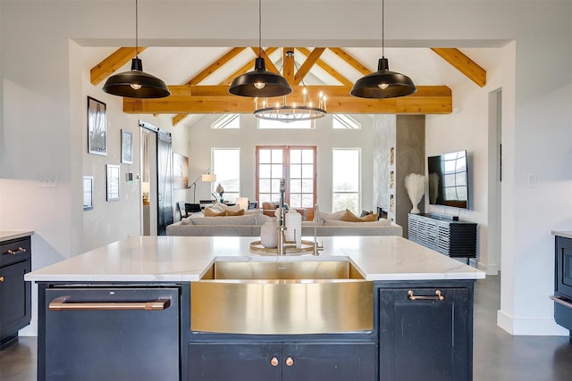 kitchen with a barn door, lofted ceiling with beams, open floor plan, and a sink