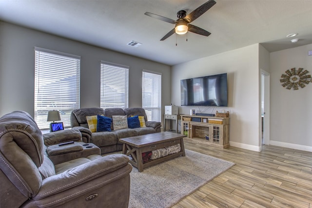 living area featuring light wood-type flooring, visible vents, baseboards, and a ceiling fan