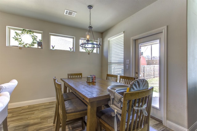 dining space featuring a chandelier, visible vents, baseboards, and wood finished floors