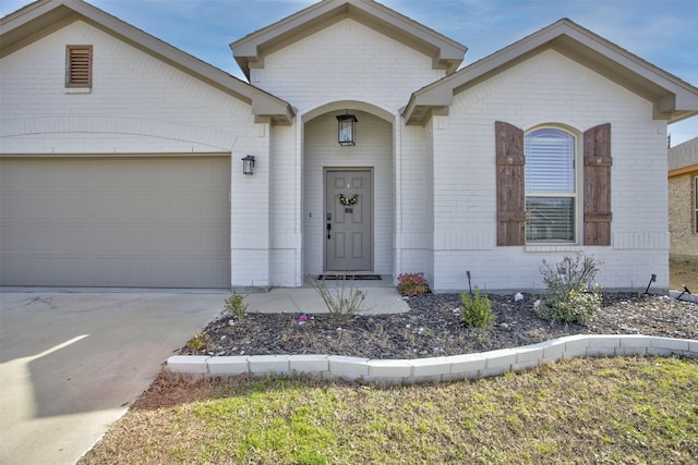 view of front of house with a garage, concrete driveway, and brick siding