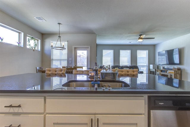 kitchen with a sink, visible vents, white cabinets, open floor plan, and stainless steel dishwasher