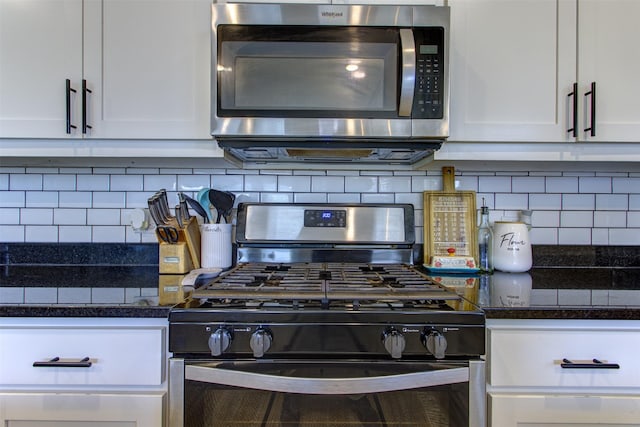 kitchen featuring dark stone counters, stainless steel appliances, backsplash, and white cabinetry