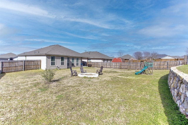 view of yard featuring a fenced backyard, a playground, and a fire pit