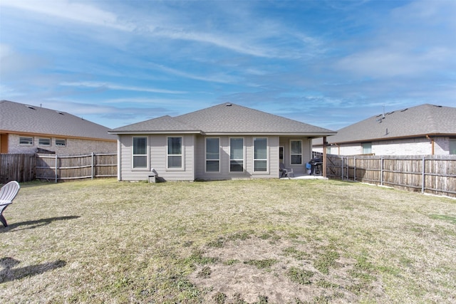 back of house featuring a yard, a shingled roof, and a fenced backyard