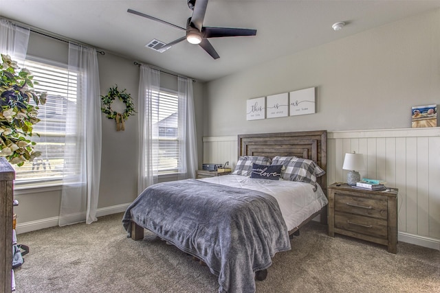 carpeted bedroom with baseboards, multiple windows, visible vents, and a ceiling fan