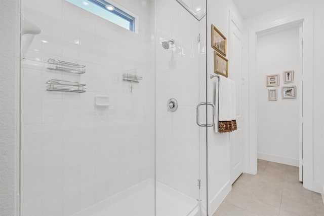 bathroom with a stall shower, baseboards, and tile patterned floors