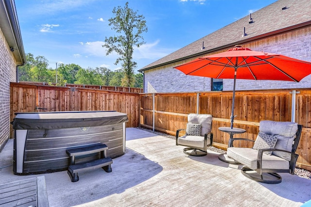 view of patio / terrace featuring a hot tub and fence