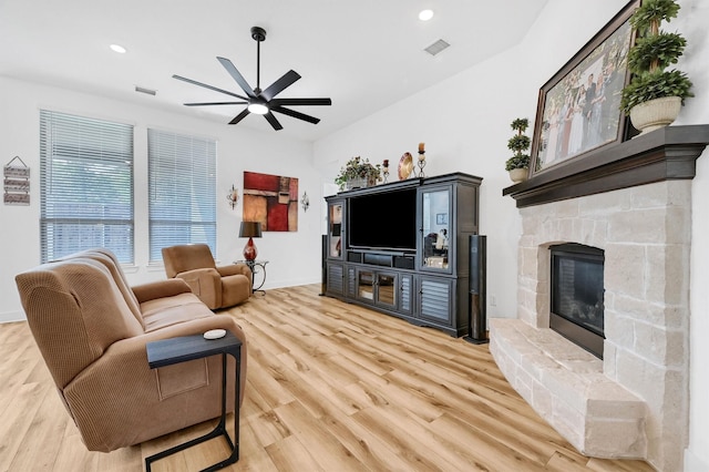 living area featuring recessed lighting, visible vents, light wood-style floors, ceiling fan, and a stone fireplace