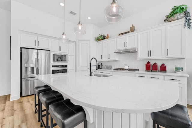 kitchen featuring tasteful backsplash, visible vents, appliances with stainless steel finishes, white cabinets, and a sink