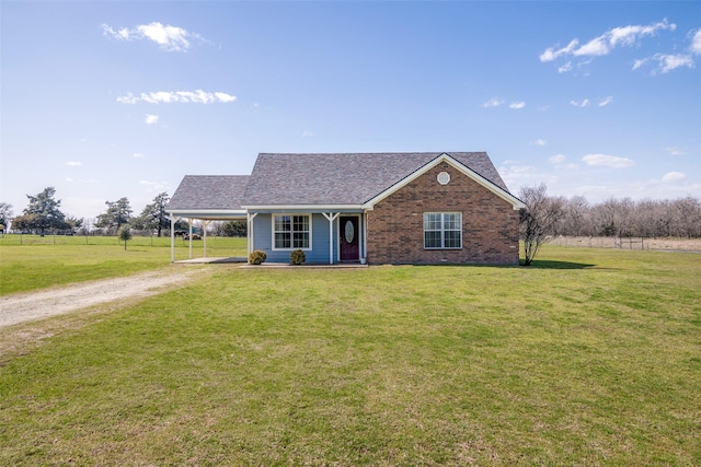 view of front of home with driveway, roof with shingles, a front yard, a carport, and brick siding