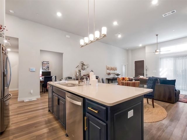 kitchen featuring visible vents, appliances with stainless steel finishes, open floor plan, light wood-type flooring, and a sink