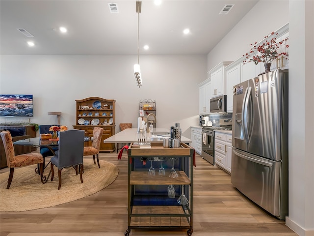 kitchen with appliances with stainless steel finishes, light wood-type flooring, and visible vents