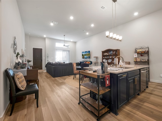 kitchen with light wood-style floors, visible vents, a sink, and an island with sink