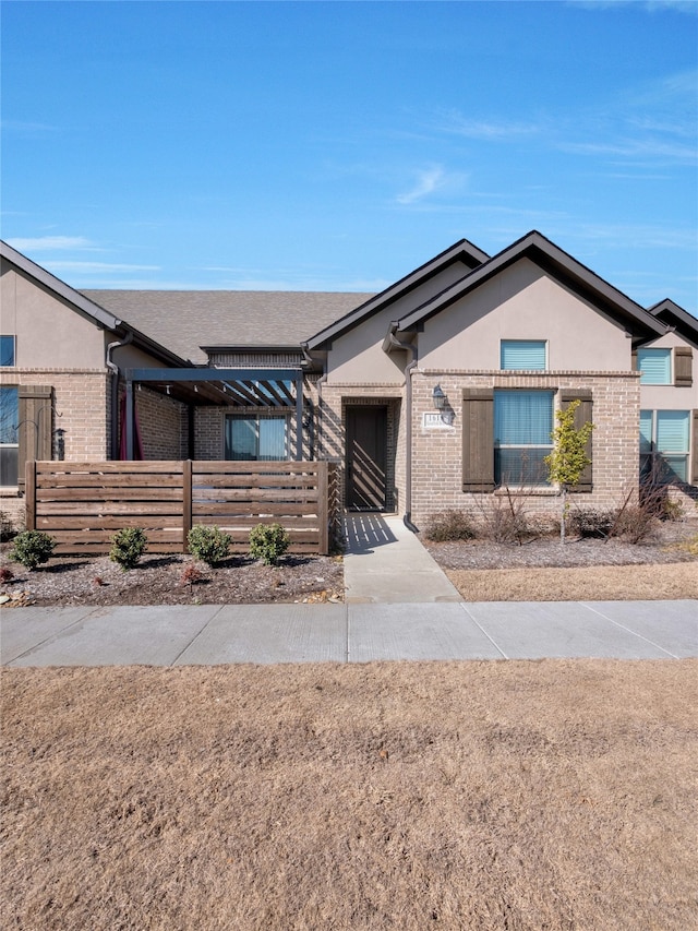 ranch-style house featuring brick siding, fence, and stucco siding