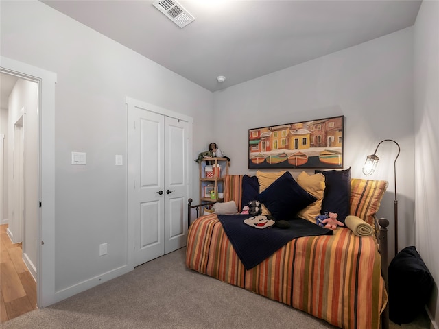 carpeted bedroom featuring baseboards, visible vents, and a closet