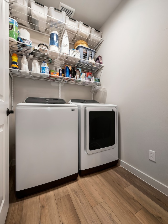 clothes washing area featuring laundry area, independent washer and dryer, wood finished floors, and baseboards