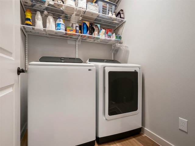 laundry room with laundry area, separate washer and dryer, wood finished floors, and baseboards