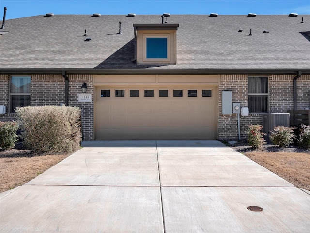 view of front of house featuring a garage, brick siding, and a shingled roof