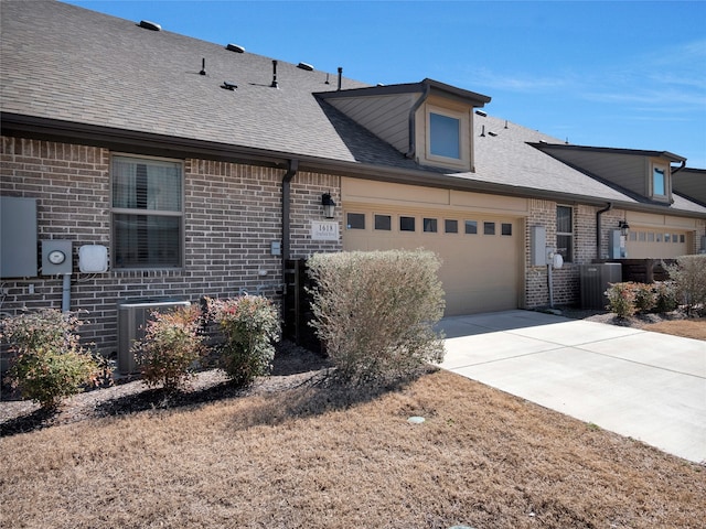 view of front of home featuring a garage, a shingled roof, concrete driveway, and brick siding