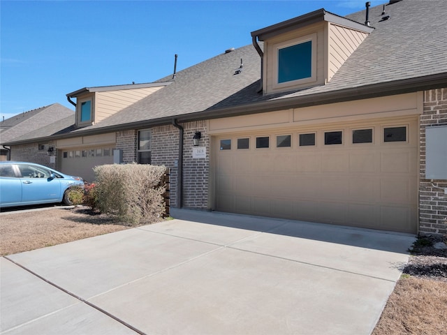 view of side of property featuring a garage, brick siding, a shingled roof, and driveway