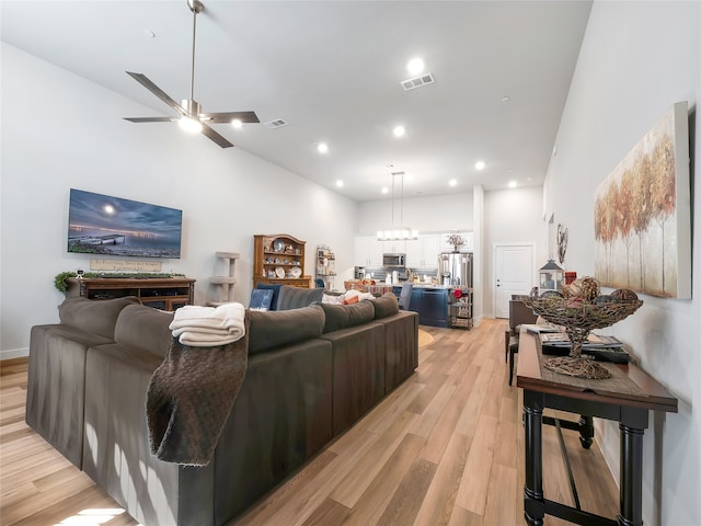 living room with recessed lighting, visible vents, a high ceiling, light wood-style floors, and a ceiling fan