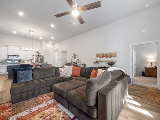 living room with high vaulted ceiling, light wood-style flooring, and visible vents