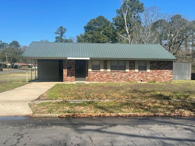 ranch-style home featuring metal roof, an attached carport, brick siding, and driveway